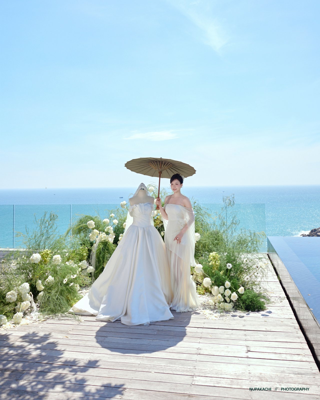 Cặp đôi che ô trên boong gỗ hướng biển